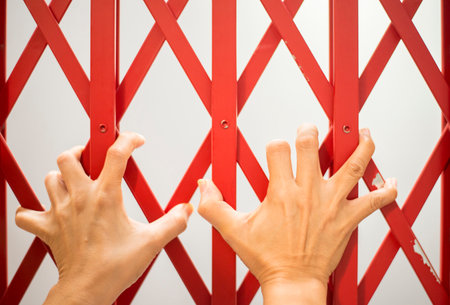 The hands of the person holding the fence of the cage were quarantine and blocked.の写真素材
