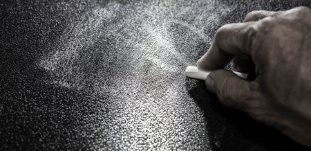 The person's hand is writing on a black backgroundの写真素材
