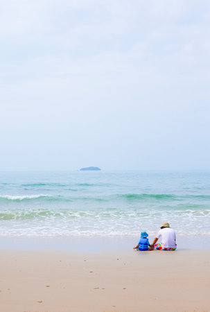 A family photo of a father with a child playing on the beach by the sea.の写真素材