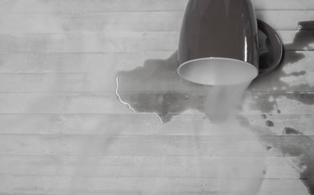 A picture of a coffee drink spilled out of glass on wood floor