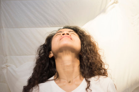 The posture of a woman sleeping on a white mattress.