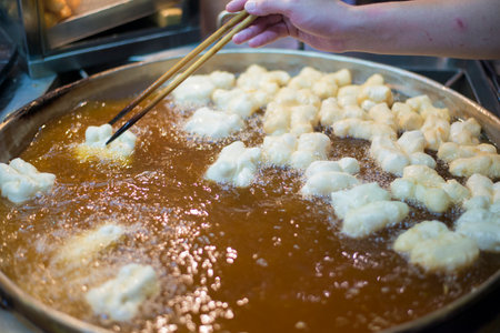 Picture of the process of making food from carbohydrate flour ingredients and frying them in hot oil.の写真素材