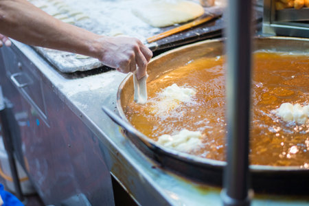 Picture of the process of making food from carbohydrate flour ingredients and frying them in hot...