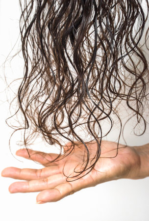 Close-up of a woman's hand with wet hair on white background
