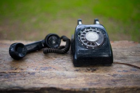 Old black telephone on wooden table with blurred green background, vintage styleの写真素材