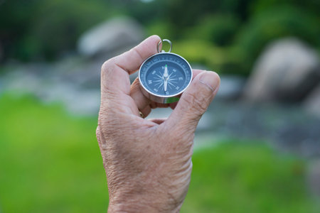 Compass in the hand of an elderly man on the background of natureの写真素材