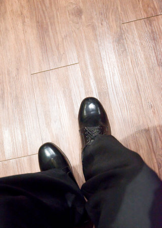 Businessman legs in black shoes on wooden floor. Top view.の写真素材