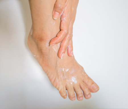 Woman washes her feet with soap and water, isolated on white backgroundの写真素材