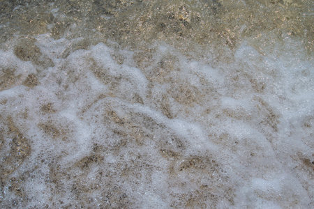 Close up of foamy water on the beach. Background and texture