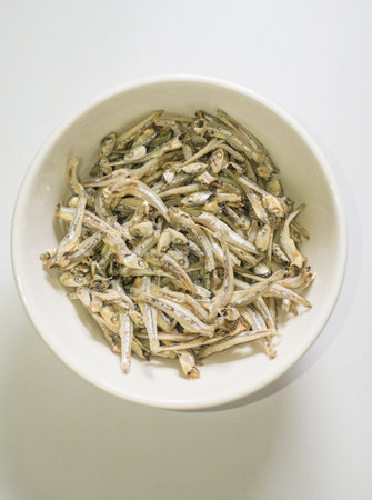 Dried anchovies in a white bowl on a white background.の写真素材