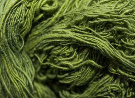 Green wool yarn as background. Close-up. Selective focus.