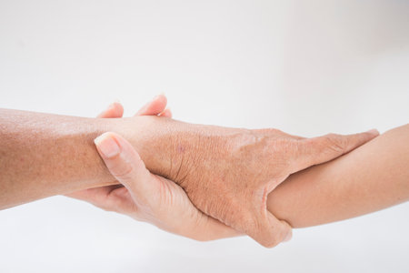 Close up of senior woman holding hand of young man on white backgroundの写真素材