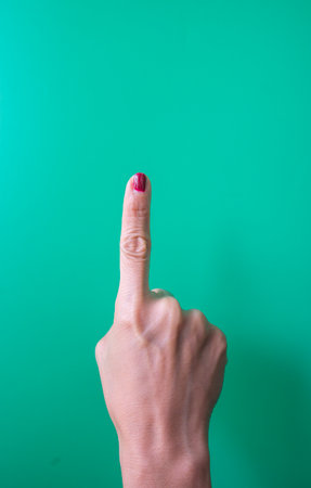 Female hand showing a finger on a green background with copyspaceの写真素材