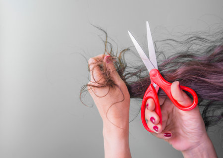 Hair loss problem concept. Woman cutting her long hair with scissorsの写真素材