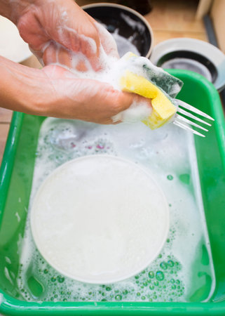 Washing dishes in the kitchen, close-up of hands.の写真素材