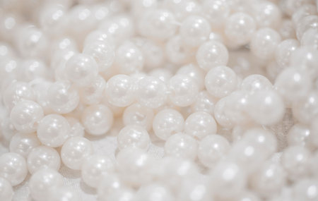 White pearl beads on white fabric background. Shallow dof.