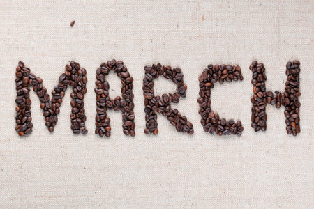 Month march written with roasted coffee beans on creamy linea canvas aligned in the center.の写真素材