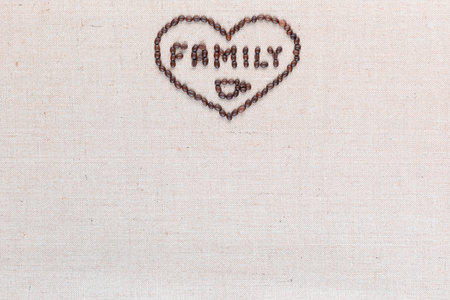 Family logo with a cup underneath enclosed in a heart shape made from roasted coffee beans on creamy linea canvas, aligned top center.の写真素材