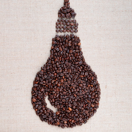 Electric bulb hanging down made from coffee beans on creamy linea canvas, shot close up.の写真素材