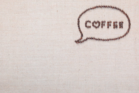 Coffee word from coffee beans enclosed in a chat cloud on creamy linen canvas shot from above, aligned on top right.の写真素材