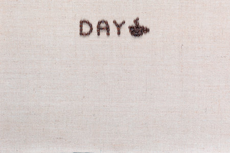 Day logo letters with a cup of coffee to the right, shot from above on creamy linen canvas aligned top center.の写真素材