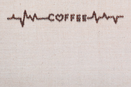 Heartbeat sign with coffee letters made from coffee beans isolated on creamy linen background aligned on top.の写真素材