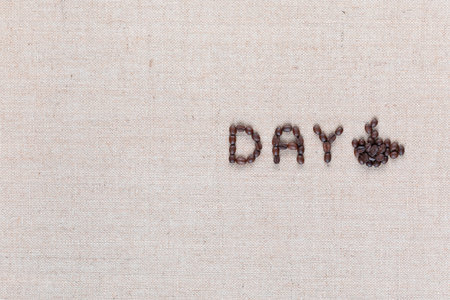 Day logo letters with a cup of coffee to the right, shot from above on creamy linen canvas aligned middle right.の写真素材