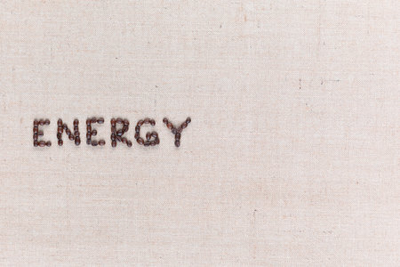 Energy word made with capital letters from roasted coffee beans on creamy linen canvas, shot from above, aligned middle left.の写真素材