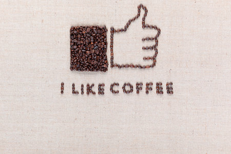 I like coffee letters and a thumbs up icon, made from roasted coffee beans on creamy linen canvas, aligned top center.の写真素材