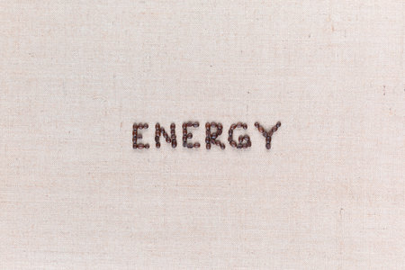 Energy word made with capital letters from roasted coffee beans on creamy linen canvas, shot from above, aligned in center.の写真素材