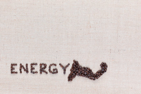 Energy word with a muscle icon made from roasted coffee beans on creamy linen canvas, shot from above, aligned bottom.の写真素材