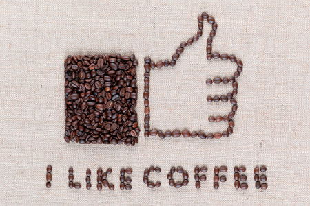 I like coffee letters and a thumbs up icon, made from roasted coffee beans on creamy linen canvas, shot close up.の写真素材