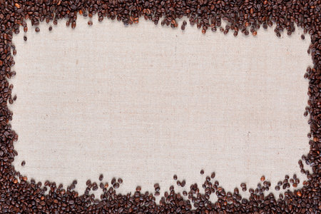 Roasted coffee beans in large amount with open space at center on linen canvas.の写真素材