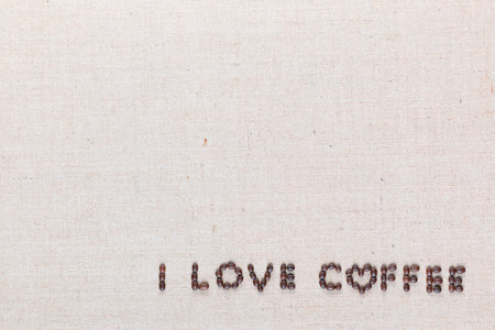 'I love coffee' words made from roasted coffee beans on linen texture, shot from above, aligned bottom right.の写真素材