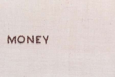 Money word from roasted coffee beans on creamy linen canvas, shot from above, aligned middle left.の写真素材