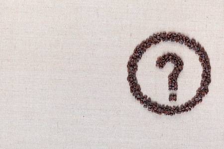 Question mark enclosed in circle made from coffee beans on creamy linen fabric, shot from above, aligned middle right.の写真素材