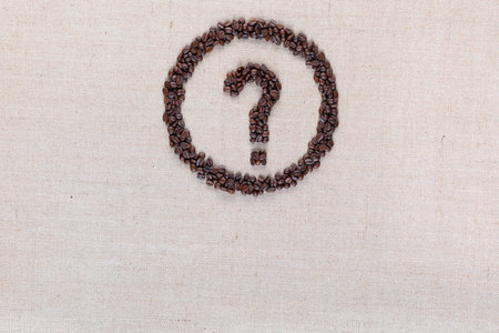 Question mark enclosed in circle made from coffee beans on creamy linen fabric, shot from above, aligned top center.の写真素材
