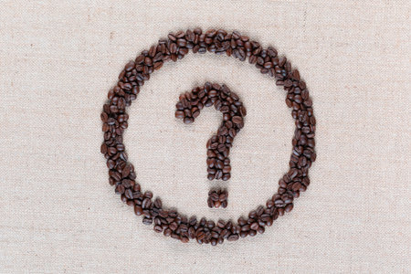 Question mark enclosed in circle made from coffee beans on creamy linen fabric, shot from above, close up.の写真素材