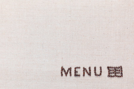 Menu word with icon made from roasted coffee beans on linen creamy linen canvas, shot from above, aligned bottom right.の写真素材