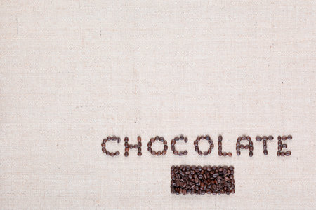 Chocolate word written with coffee beans on creamy linea canvas, shot from above, aligned in the bottom right.の写真素材