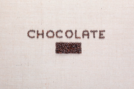 Chocolate word written with coffee beans on creamy linea canvas, shot from above, aligned in center.の写真素材