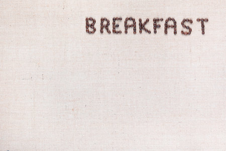 Breakfast word written with coffee beans on creamy linea canvas, shot from above,aligned in the top right.の写真素材
