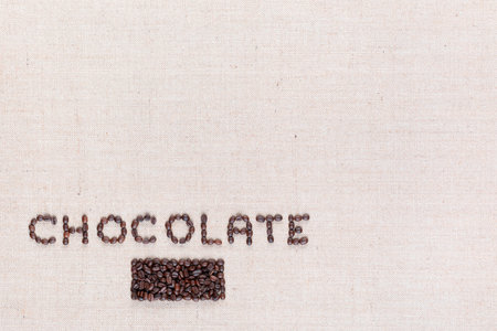 Chocolate word written with coffee beans on creamy linea canvas, shot from above, aligned in the bottom left.の写真素材