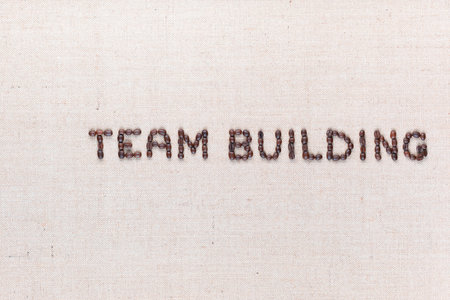 The words Team Building written with coffee beans on creamy linea canvas, shot from above, aligned to the right.の写真素材