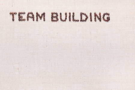 The words Team Building written with coffee beans on creamy linea canvas, shot from above, aligned at the top left.の写真素材