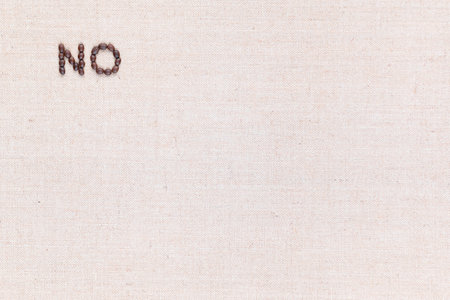 The word No written with coffee beans on creamy linea canvas, shot from above, aligned at the top right.の写真素材