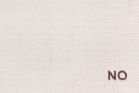 The word No written with coffee beans on creamy linea canvas, shot from above, aligned at the bottom right.の写真素材