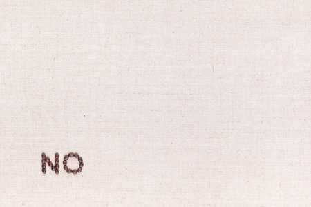 The word No written with coffee beans on creamy linea canvas, shot from above, aligned at the bottom left.の写真素材