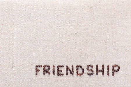 Friendship word written with coffee beans on creamy linea canvas, shot from above, aligned at the bottom right.の写真素材