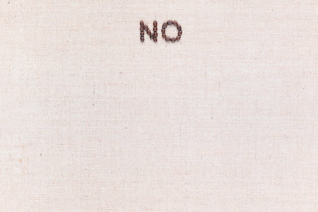 The word No written with coffee beans on creamy linea canvas, shot from above, aligned at the top.の写真素材